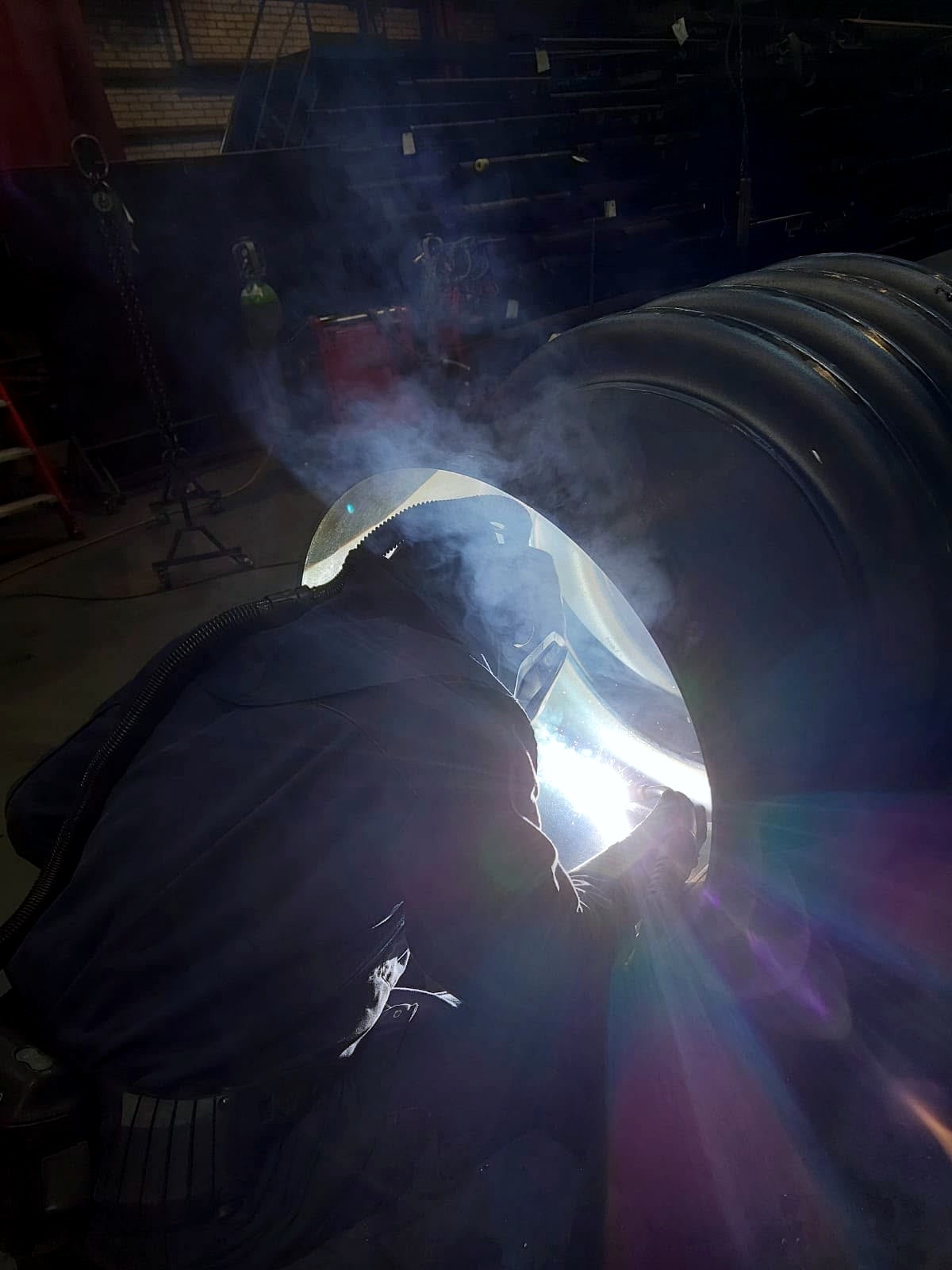 Lasser aan het werk aan een dikwandige leiding in de werkplaats