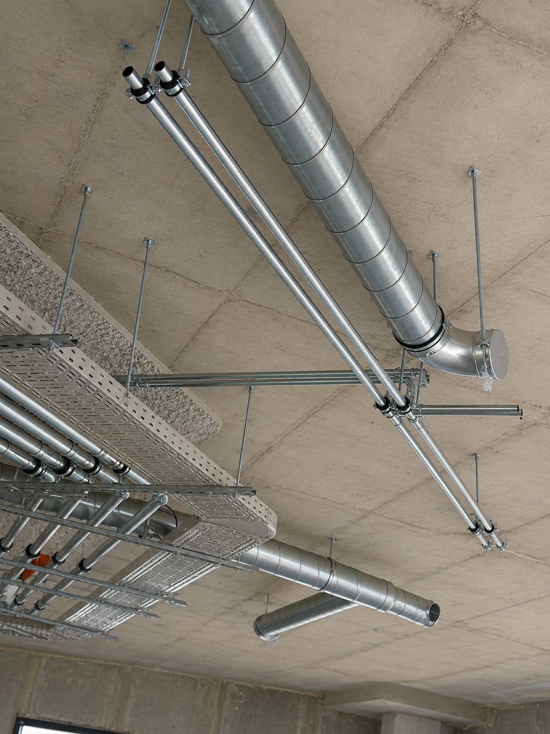 Verzinkt leidingwerk met ophangsysteem onder een betonvloer