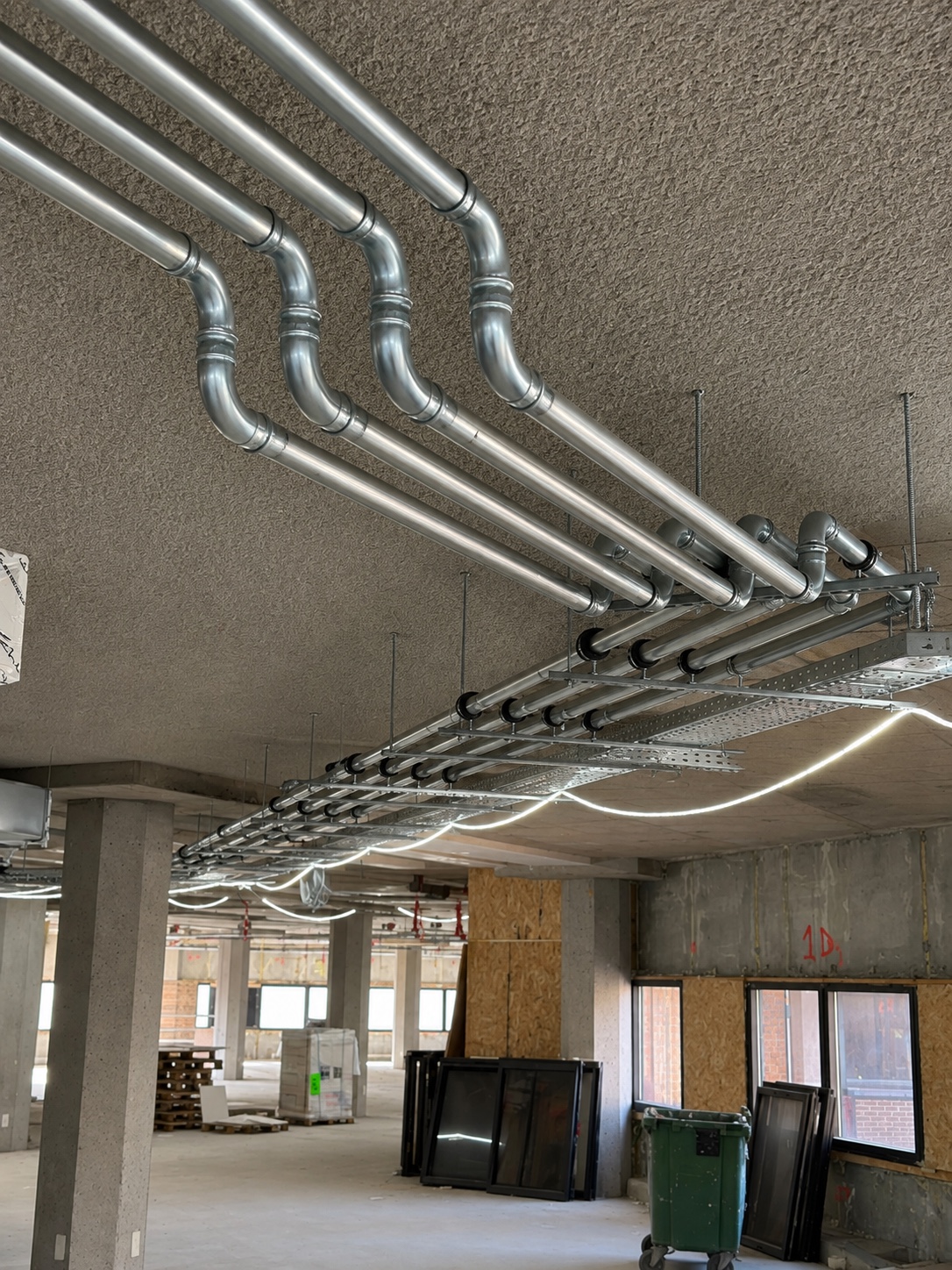 Horizontaal leidingtracé door een utiliteitsverdieping in uitvoering