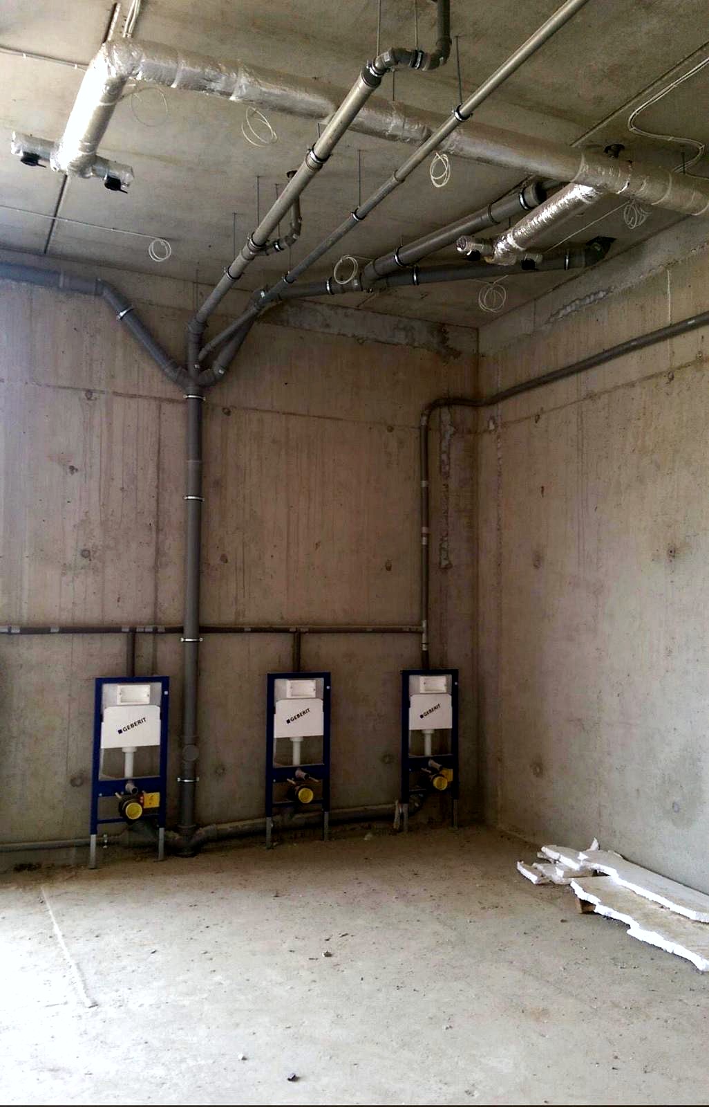 Geberit inbouwframes met leidingaansluitingen in een betonnen ruimte