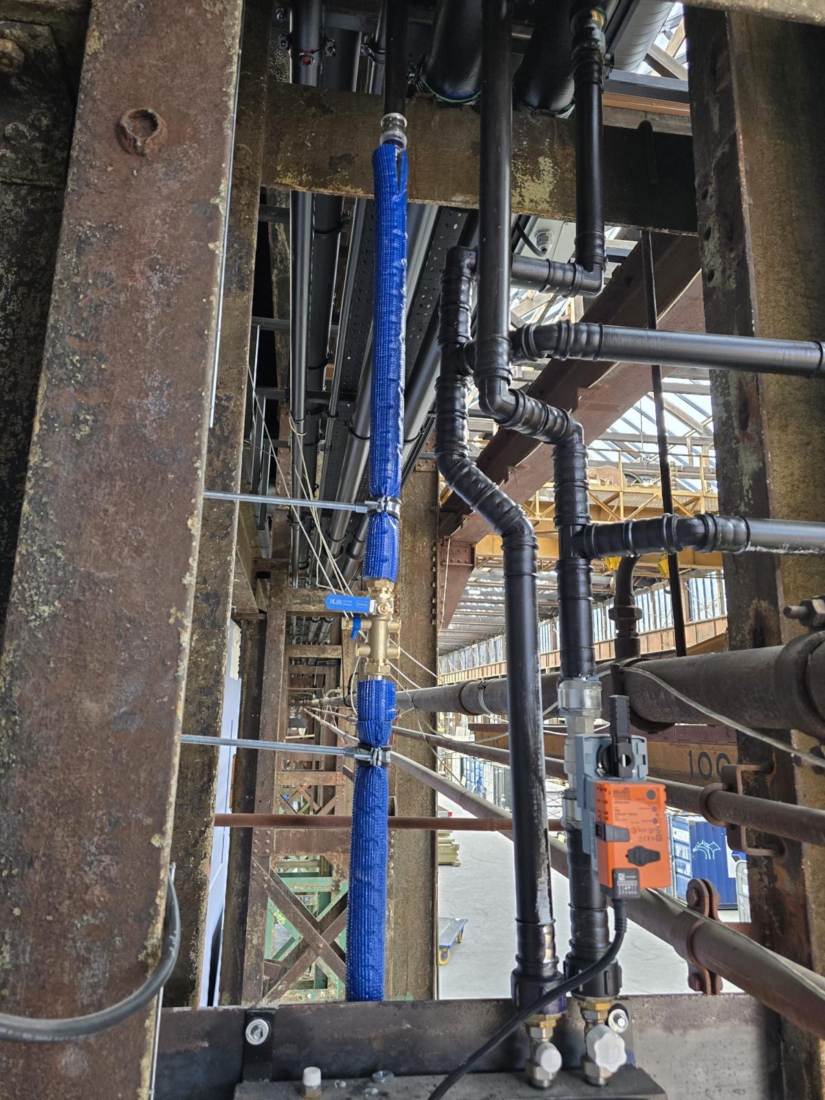 Stalen leidingwerk met aftakkingen en afsluiters in een industriële staalconstructie